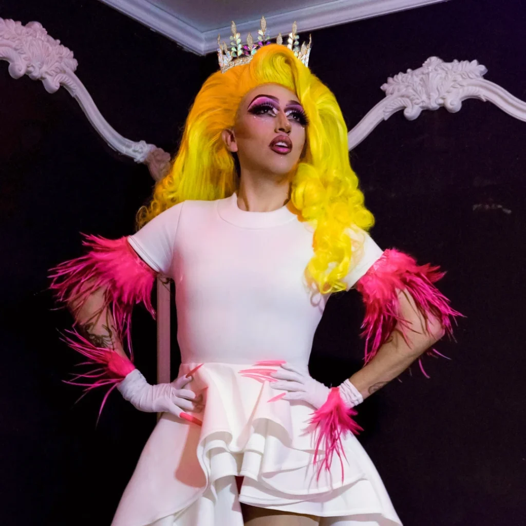 A drag queen with a long yellow wig posing for a photo