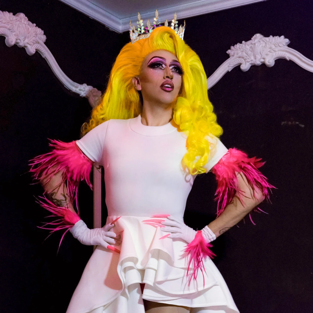 drag-show A drag queen with a long yellow wig posing for a photo