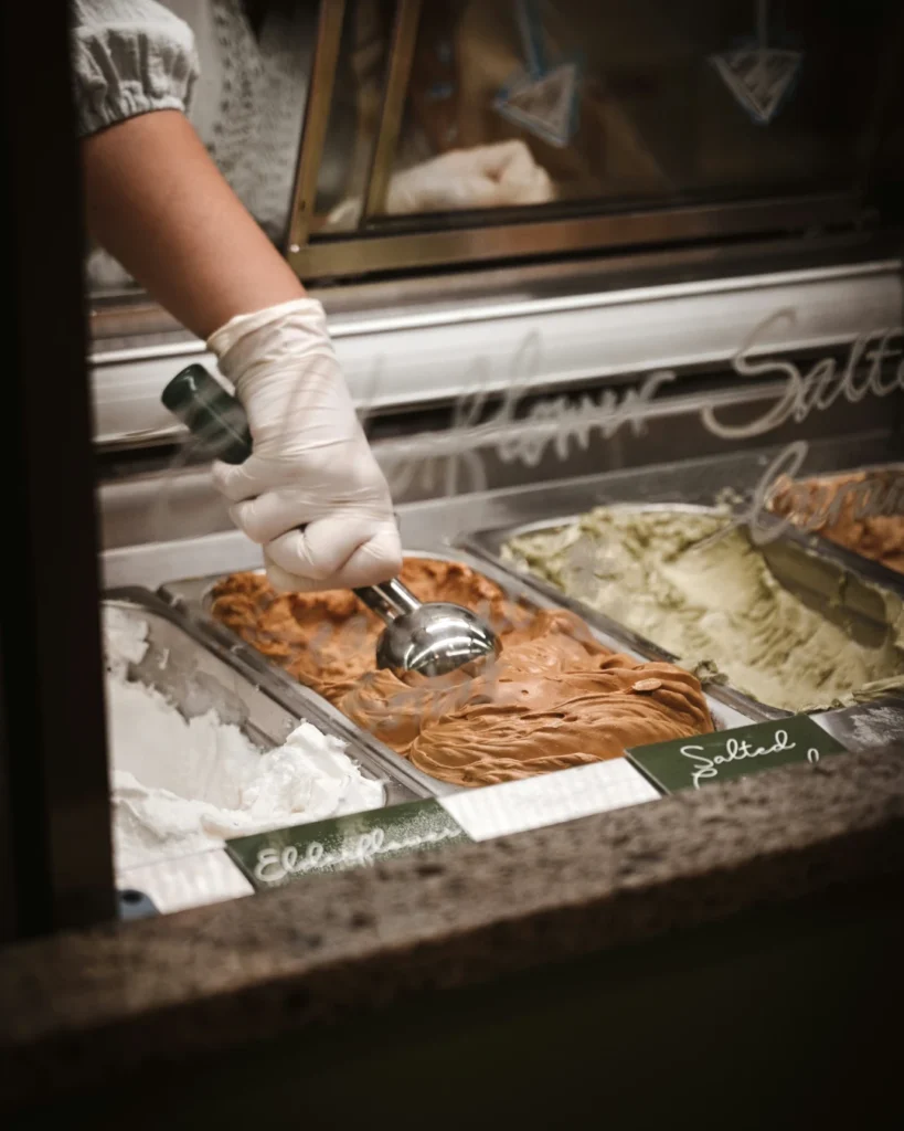 close up of a gelato shop window with server scoping icecream