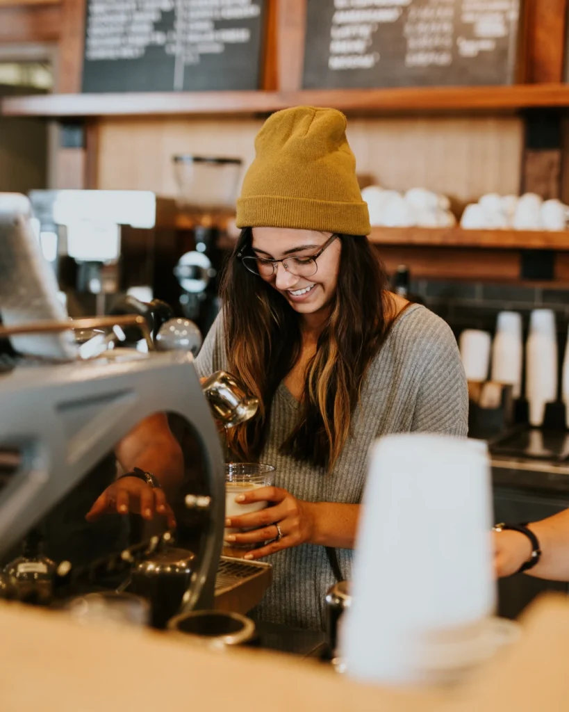 Happy female barista making coffee at a cafe