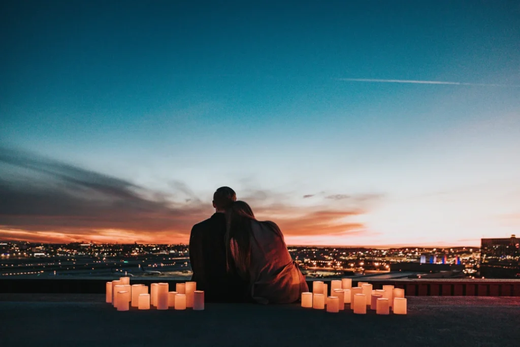 Couple sitting on a rooftop surrounded by candles at dusk