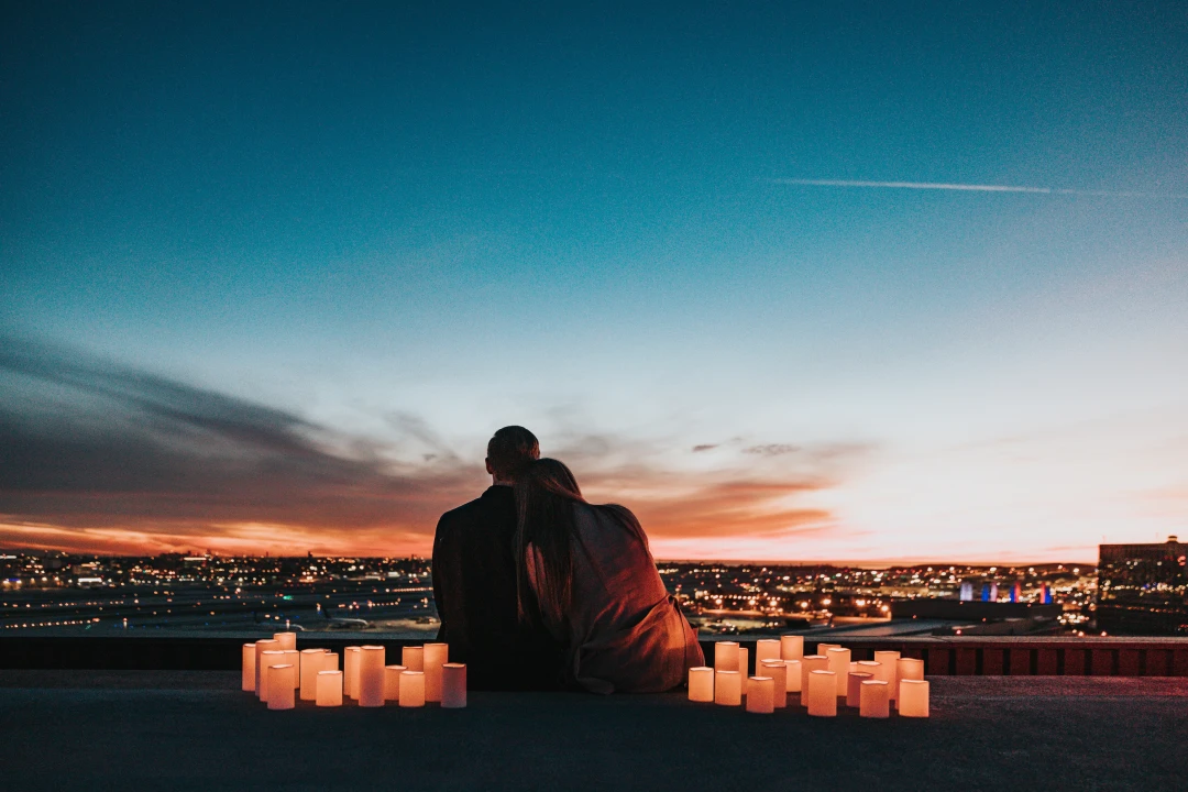 rooftop-dinner Couple sitting on a rooftop surrounded by candles at dusk