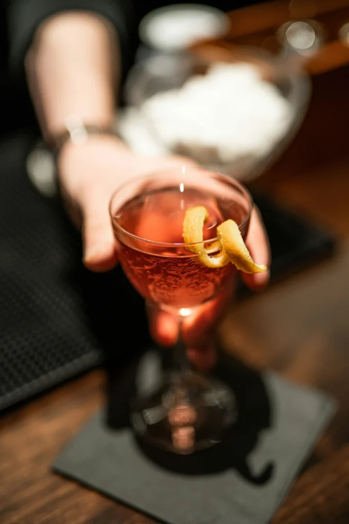 A bartender presenting a negroni cocktail