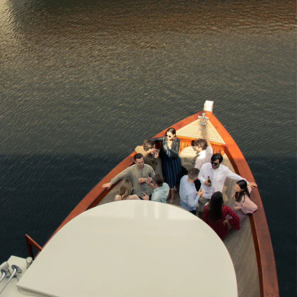 A group of people on the bow of a boat at sunset